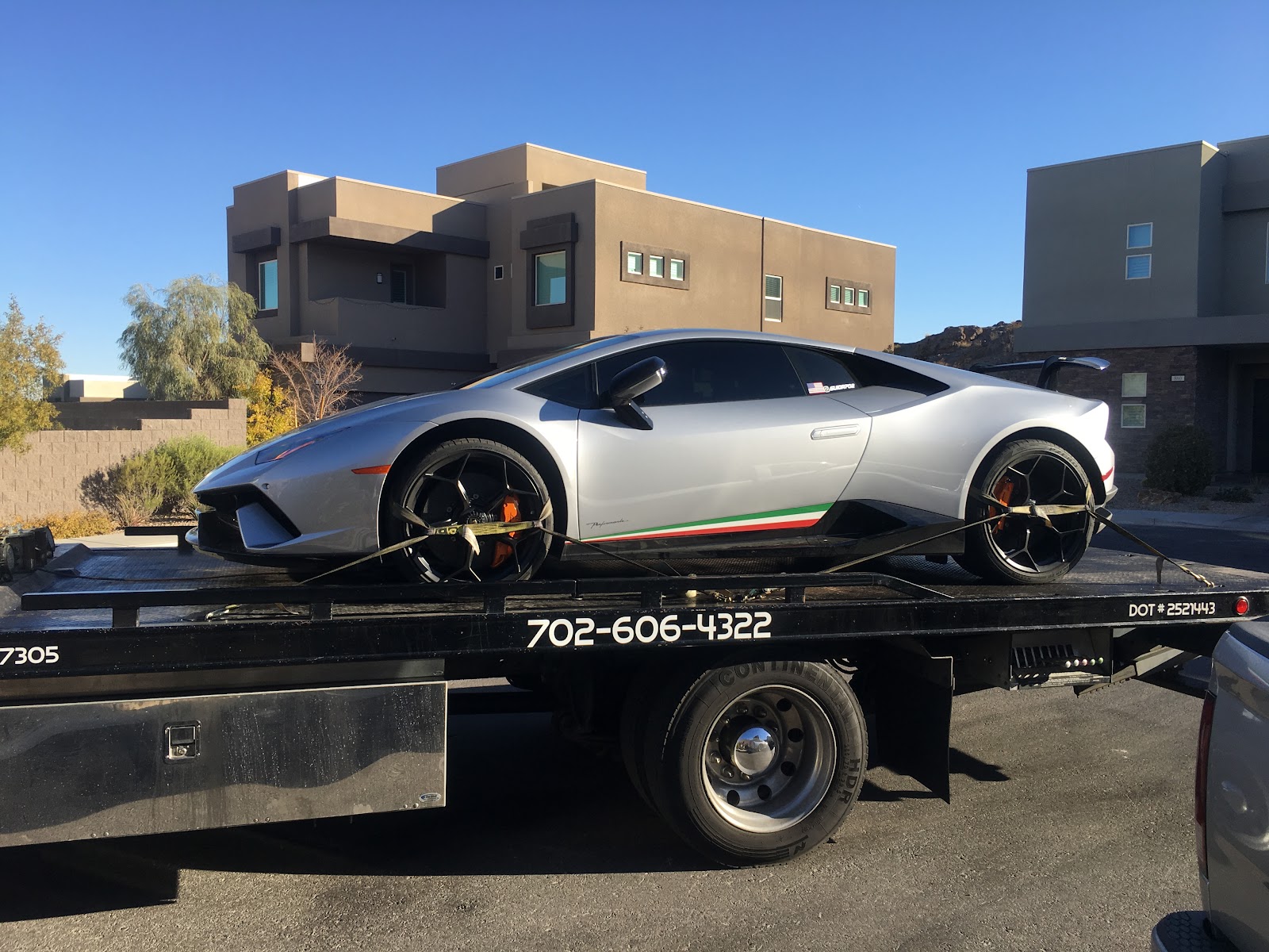 Flatbed tow truck transporting a silver Lamborghini Huracan Performante