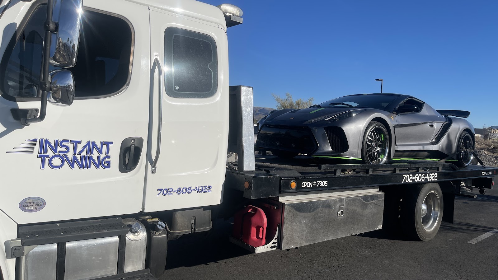 Instant Towing flatbed carrying a custom gray supercar