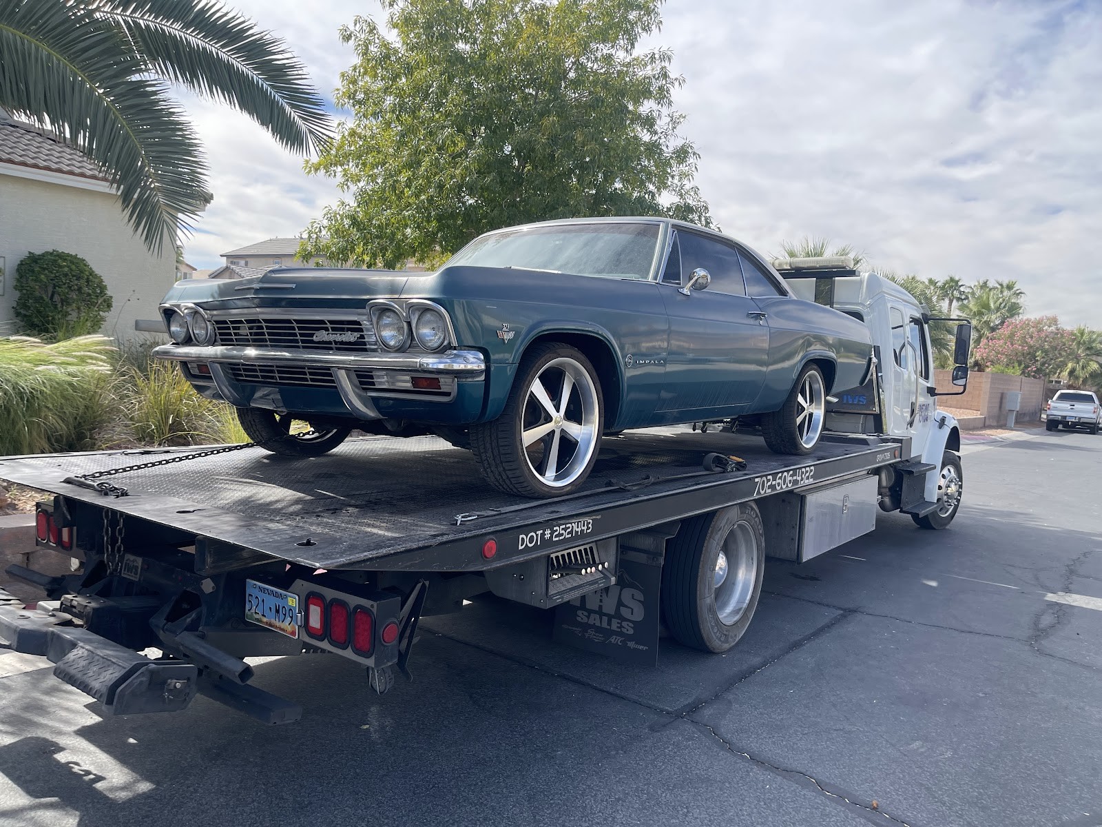 Flatbed hauling a teal classic Chevrolet Impala